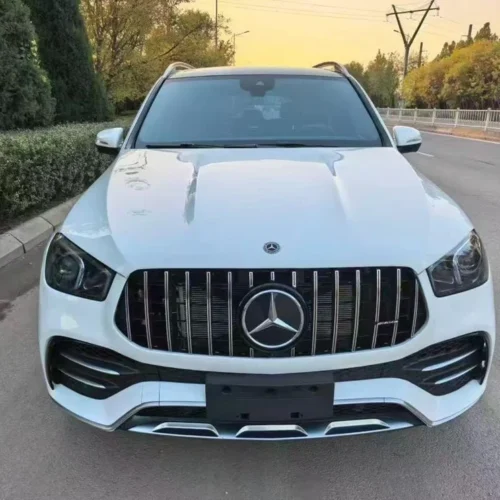 Performance-Driven Highlights (Rear View): ​Model Identification: Clearly badged as the "GLE 53" and "AMG", denoting its position as a performance-tuned model. ​AMG Exhaust System: Features a quad-outlet exhaust (four round tailpipes) integrated into the rear diffuser, which signifies the potent AMG-enhanced 3.0L inline-six turbo engine. This exhaust is known for its performance symphony, which can be conducted via AMG DYNAMIC SELECT. ​Sporty Rear Diffuser: The prominent lower rear valance/diffuser adds an aggressive, aerodynamic look, typical of AMG's styling cues. ​Modern LED Taillights: Equipped with sleek LED taillamps for a sophisticated, modern light signature and superior visibility. ​SUV Utility: Features a power liftgate and ample cargo capacity behind the rear seats, providing the necessary practicality of an SUV